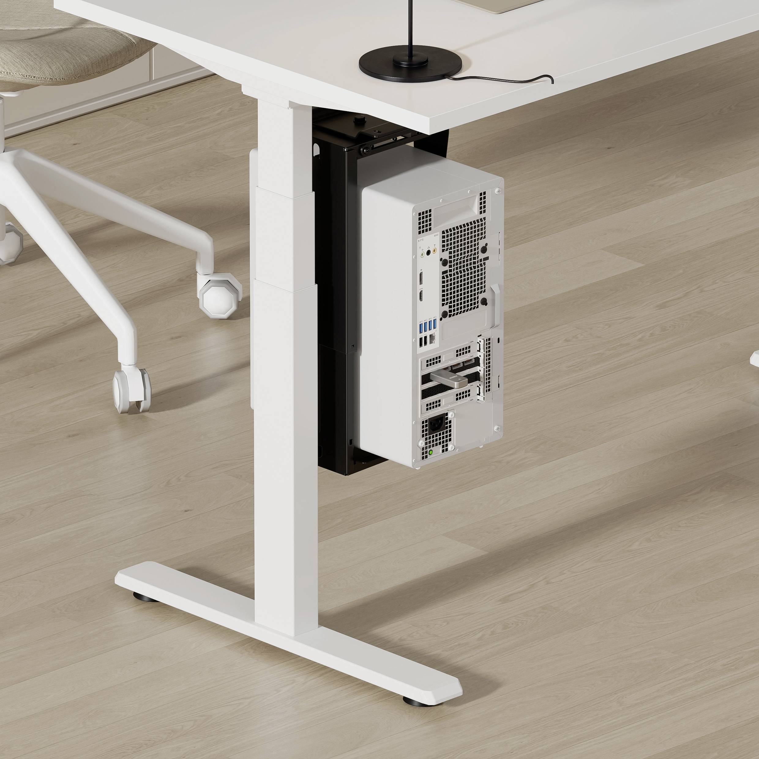 Een wit bureau heeft een ondergemonteerde computerbehuizing met zichtbare poorten, rustend op een lichte houten vloer. Een stoelpoot is gedeeltelijk zichtbaar.
