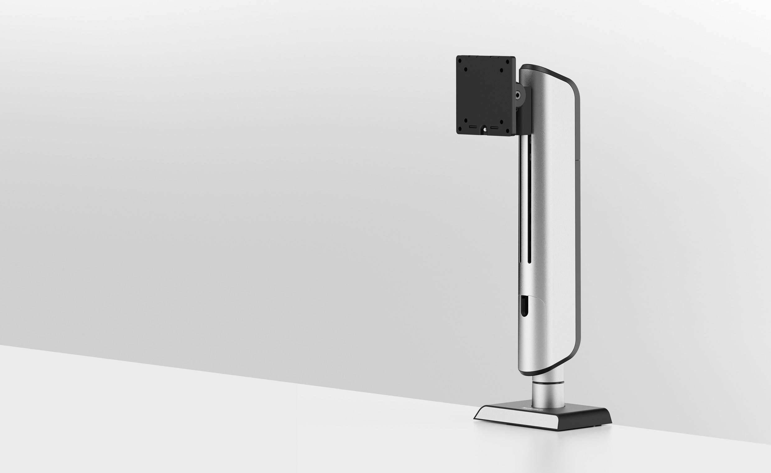 Een strak, modern monitorstatief met een metaalkleurige afwerking staat op een wit oppervlak tegen een lichtgrijze achtergrond.
