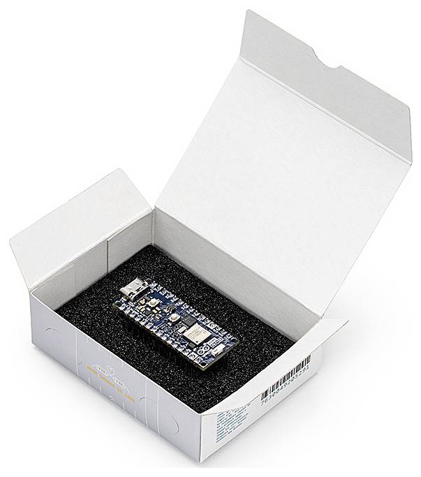 Een elektronische microcontroller-board ligt in een half geopende witte doos op zwart schuimvulling.