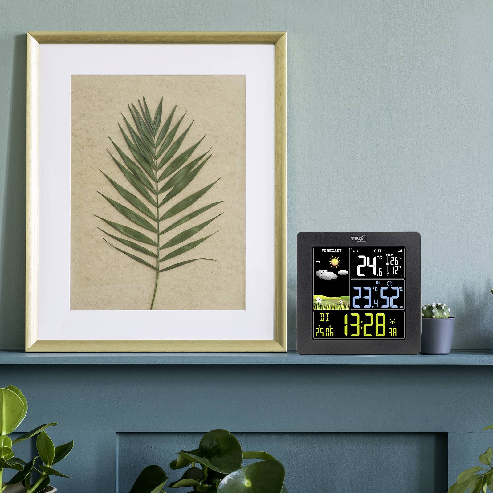 Een digitaal weerstation toont temperatuur, luchtvochtigheid en tijd aan. Ernaast staat een afbeelding met een groen palmenblad.