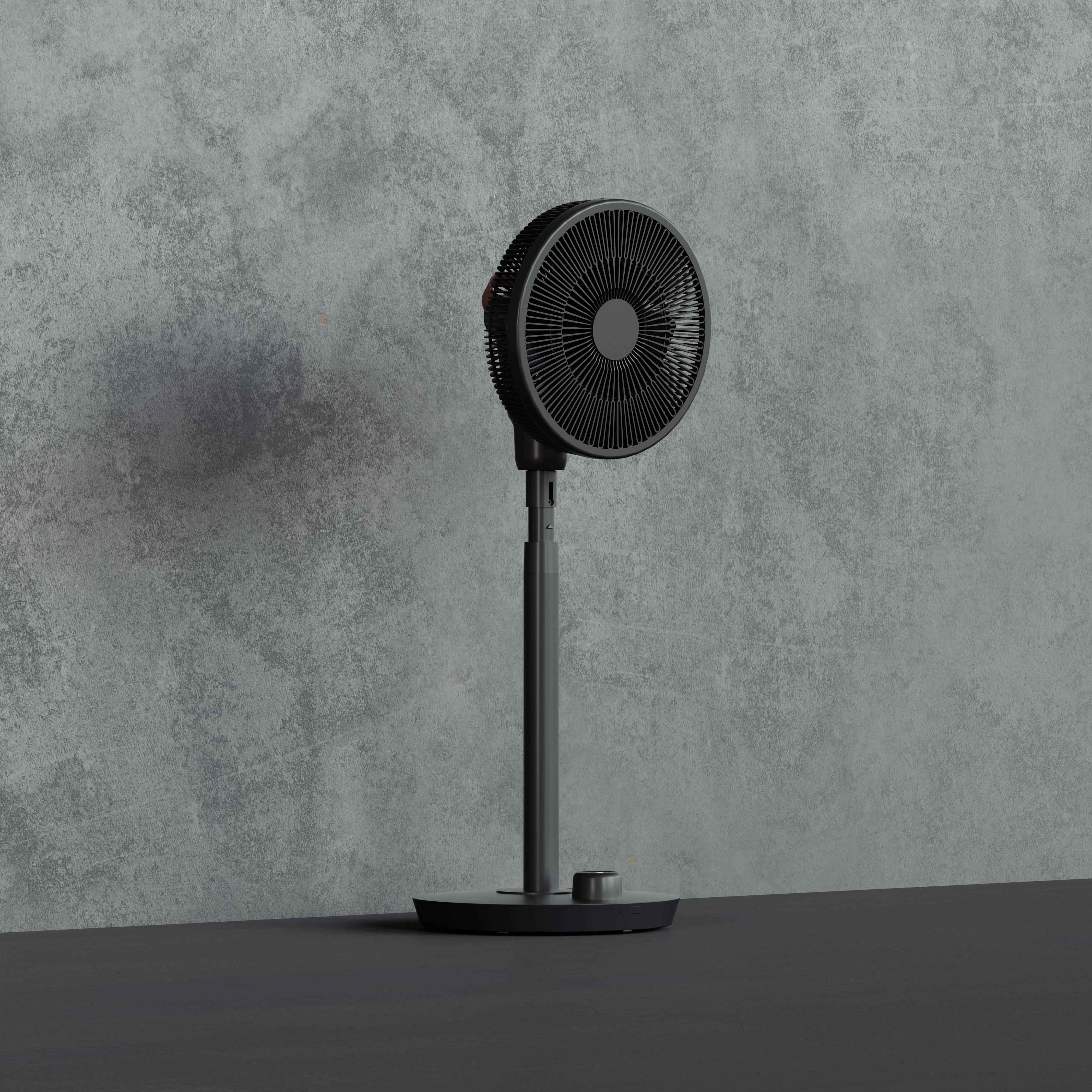 Een zwarte, moderne staande ventilator voor een grijze muur. De ventilator staat op een smalle voet en oogt minimalistisch.