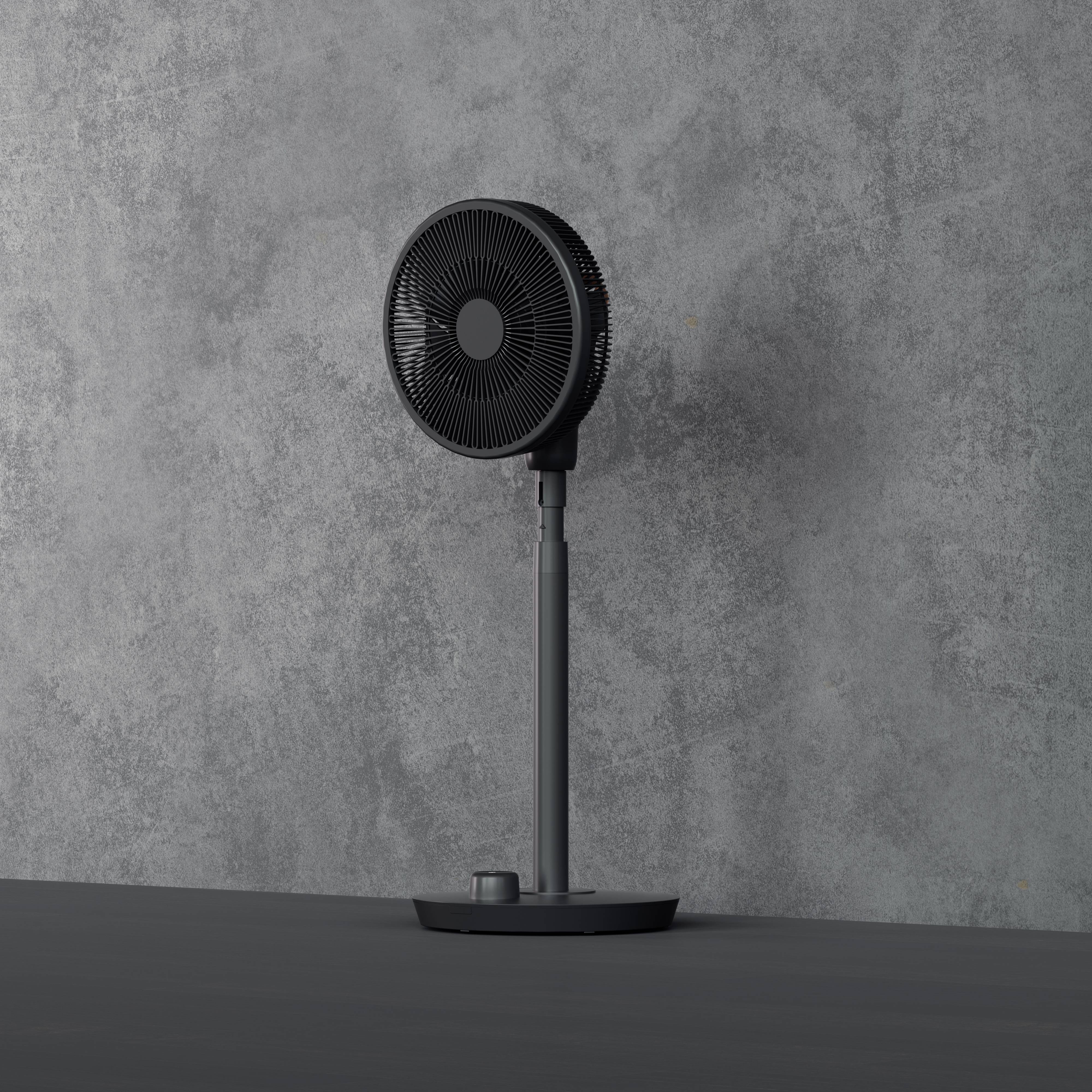 Een zwarte staande ventilator staat voor een grijze betonnen muur op een gladde vloer.