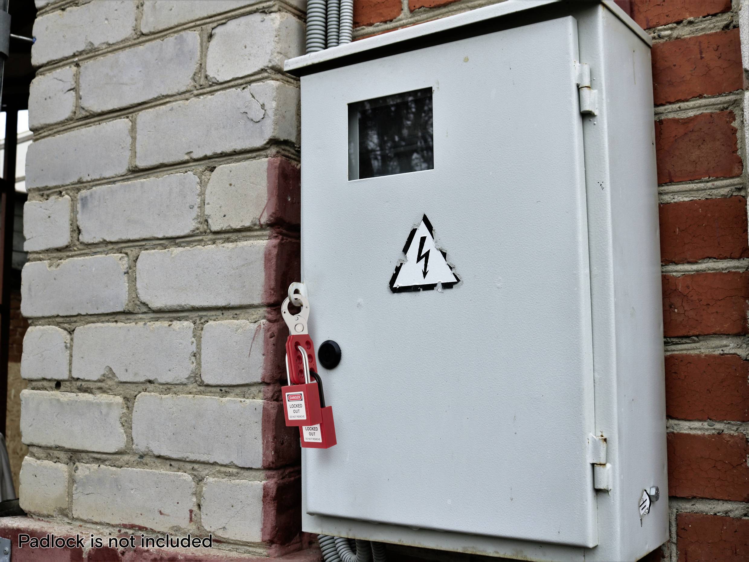 Elektrisch paneel gemonteerd op een bakstenen muur met een hoogspanningswaarschuwingssymbool. Een rode vergrendelingswaarschuwingstag is bevestigd, wat beperkte toegang aangeeft.