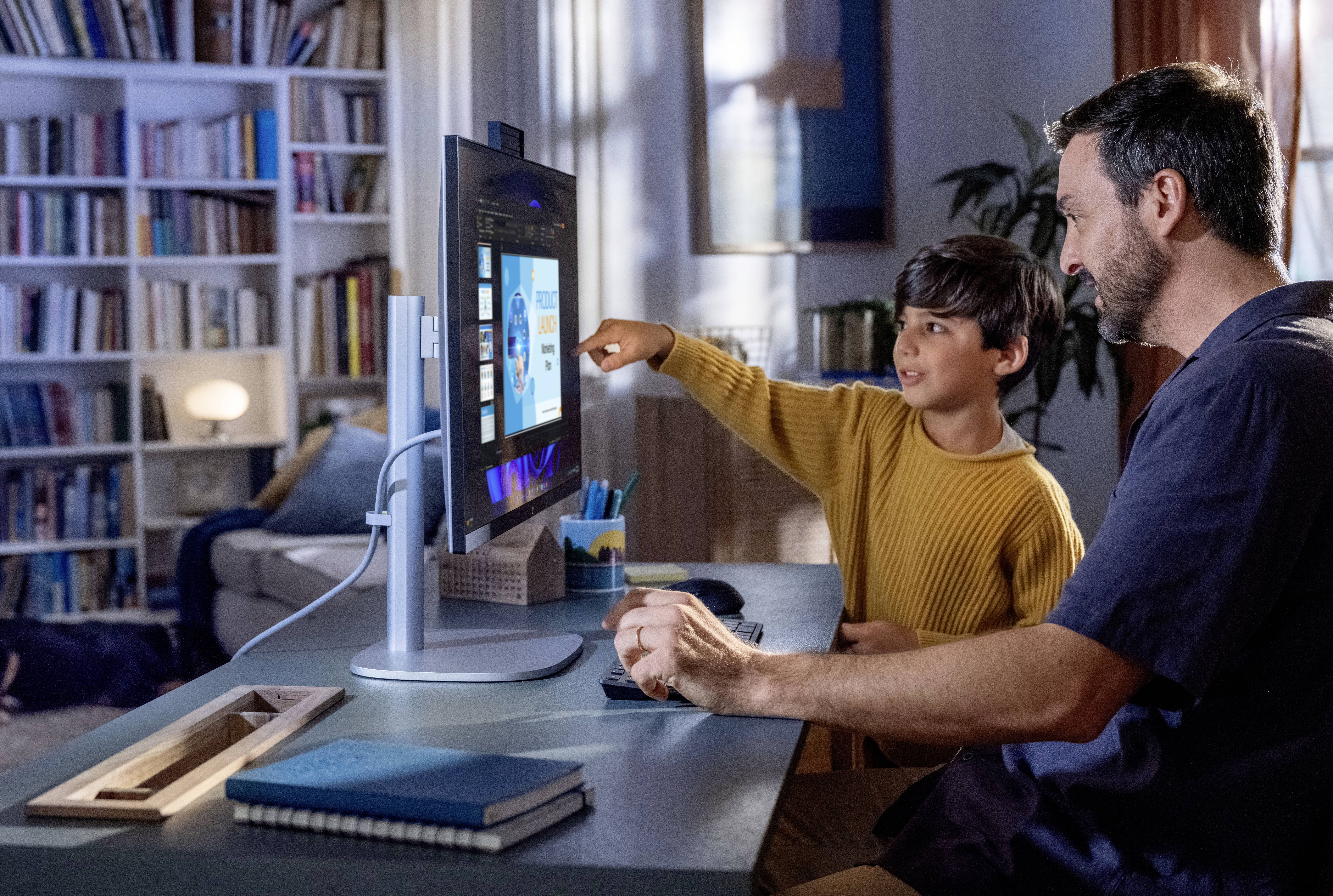 Een man en een jongen kijken samen naar een computerscherm in een gezellige, met boeken gevulde ruimte, gericht op een educatieve presentatie.