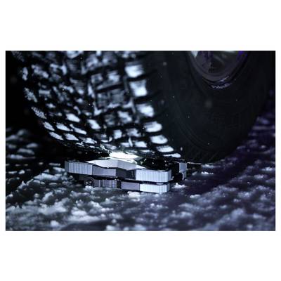 Close-up van een voertuigwiel en onderstel rustend op sneeuw of ijs, met nadruk op een compact metalen tractieapparaat onder de band.