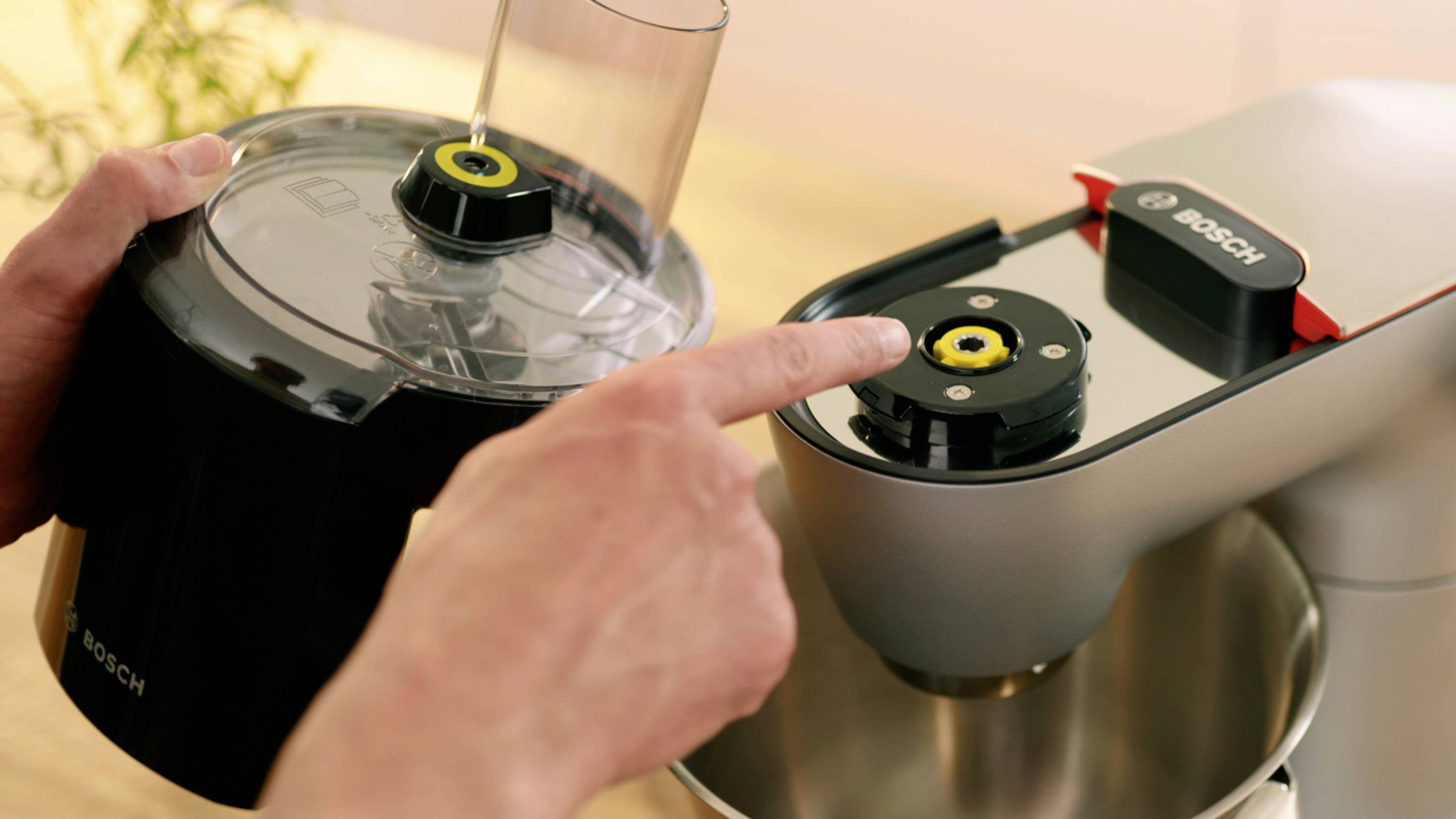 Handen bevestigen een onderdeel van een Bosch keukenmixer, waarbij wordt getoond hoe componenten correct in elkaar gezet moeten worden.