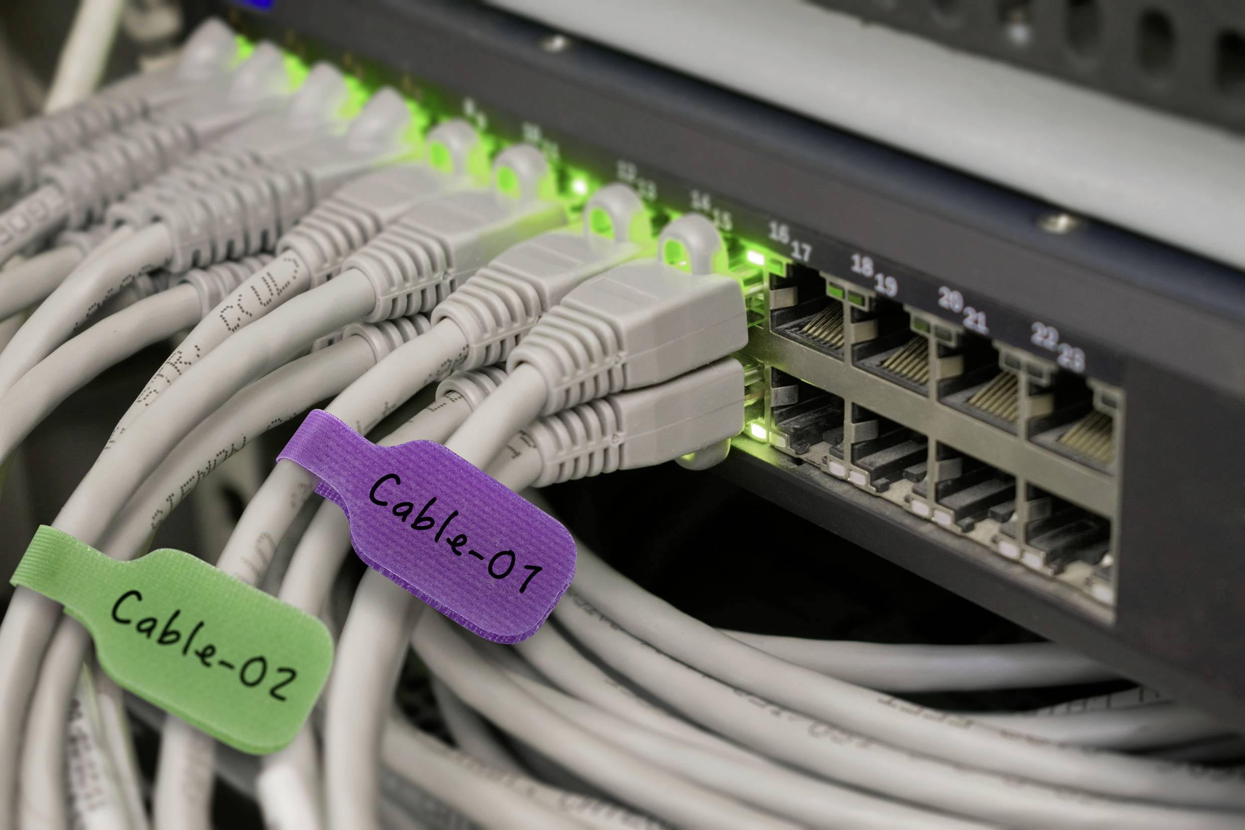 Netwerkkabels aangesloten op een server, gelabeld als 'Kabel-01' en 'Kabel-02', met groene statuslampjes die actieve verbindingen aangeven.