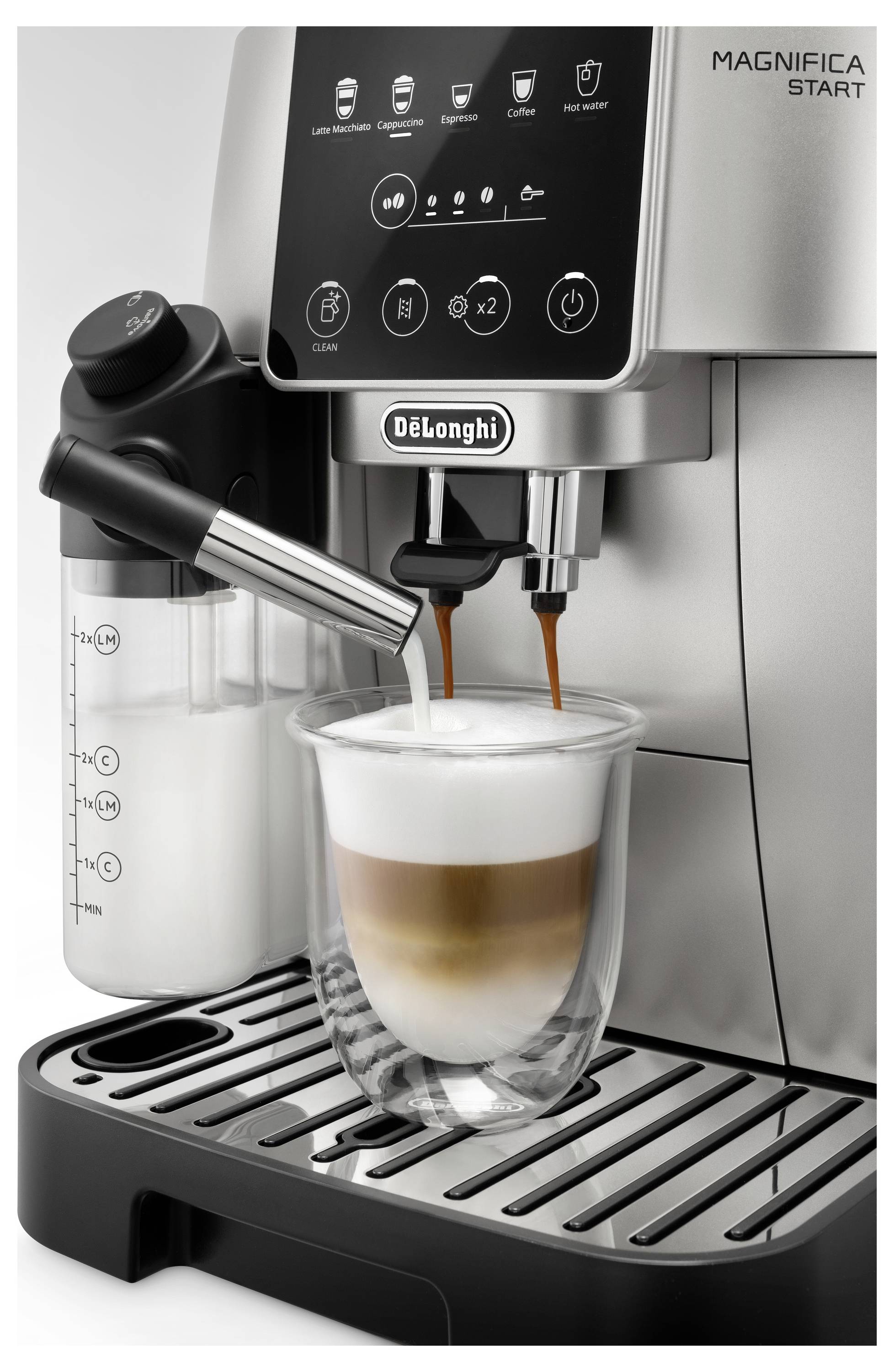 Een zilveren koffiemachine die een gelaagde cappuccino bereidt met melkschuim. De logo's van 'Magnifica Start' en 'De'Longhi' zijn zichtbaar.