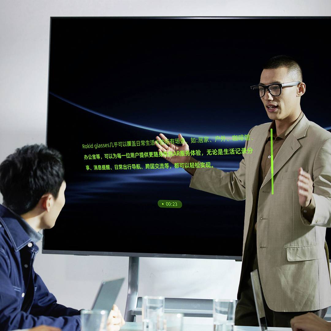 Een persoon in een pak gebaart terwijl hij spreekt voor een groot scherm met tekst. Een andere persoon luistert aandachtig.