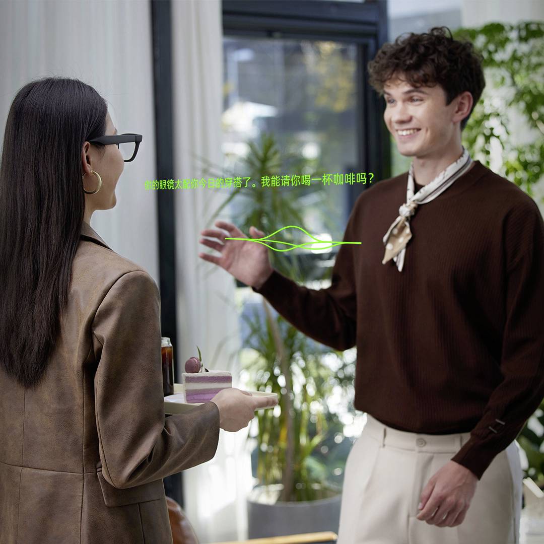 Een man en een vrouw die binnen met elkaar in gesprek zijn; ze glimlachen, wat wijst op een positieve interactie. De vrouw houdt een drankje met kersen vast.