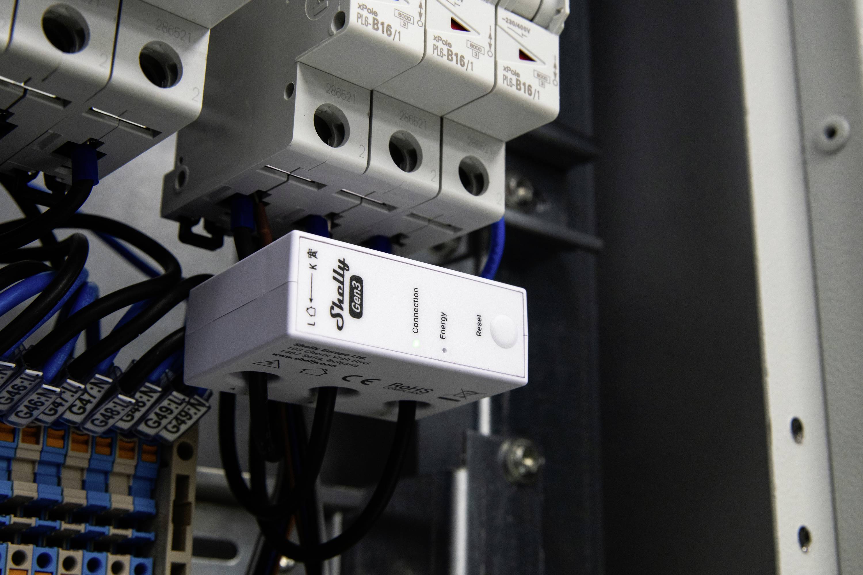 'EWSLY' gelabeld slim apparaat geïnstalleerd in een elektrisch paneel, omringd door zekeringen en bedrading, wat netwerkconnectiviteit aangeeft.