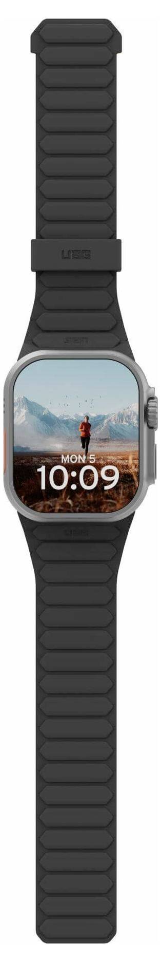 Smartwatch met een zwarte band toont de tijd '10:09' en een achtergrondafbeelding van een persoon die staat in een bergachtig landschap.