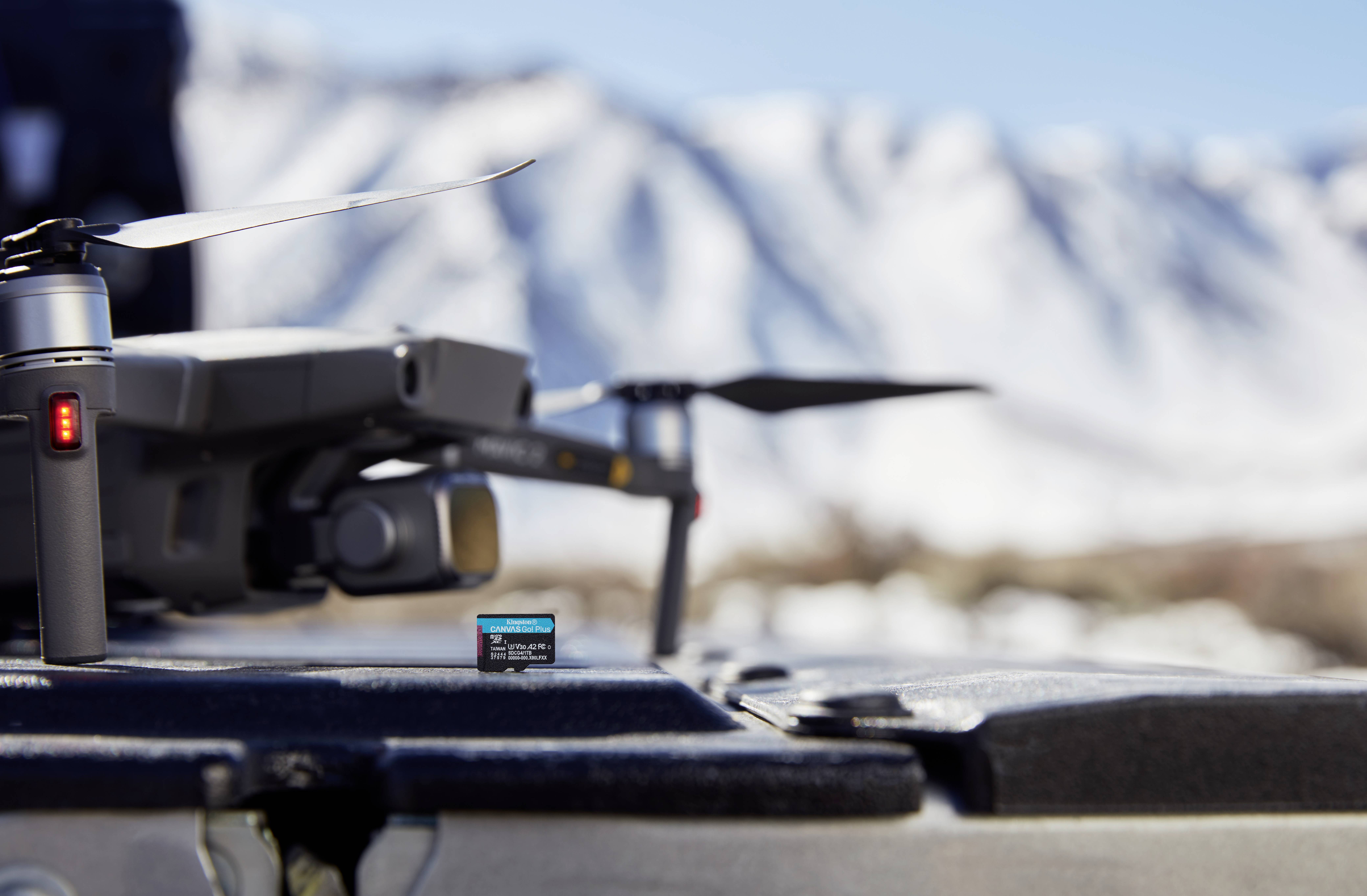 Een drone rust op een vlak oppervlak buitenshuis met met sneeuw bedekte bergen vaag op de achtergrond, wat wijst op een koud, afgelegen milieu.