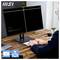 Een persoon stelt een dual-monitor opstelling in op een houten bureau. Één scherm toont ergonomische en toegankelijkheidspictogrammen. De sfeer is professioneel.