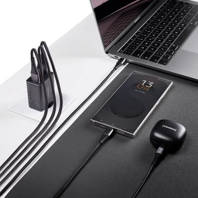 Smartphone draadloos aan het opladen op een pad naast een laptop en aangesloten oplader.