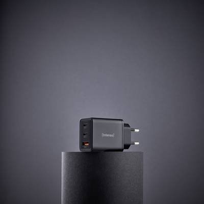 Een zwarte USB-wandlader met meerdere poorten staat op een cilindrische sokkel tegen een effen grijze achtergrond.