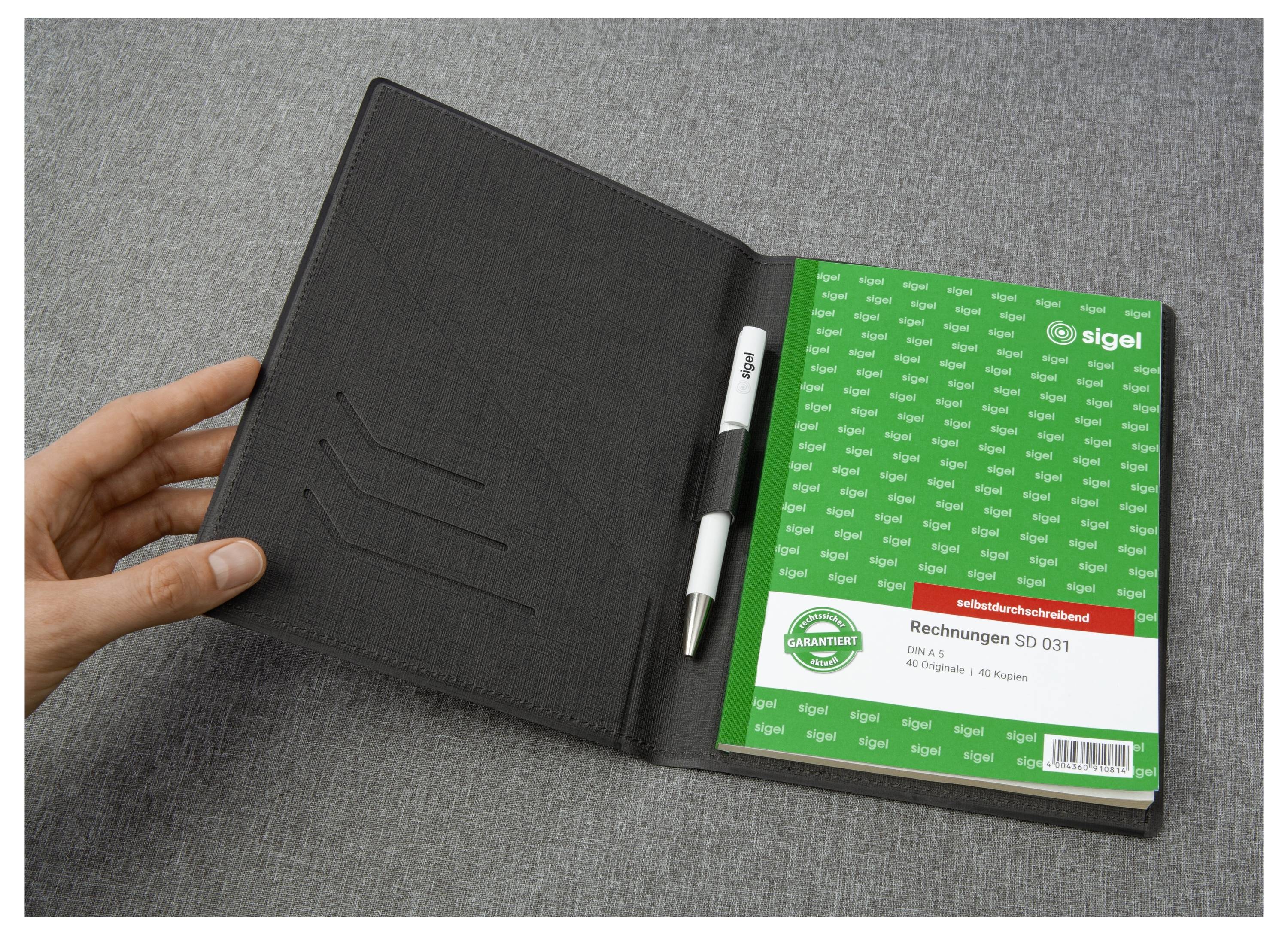 Open zwart leren portfolio met een pen en een groen Sigel factuurblok gelabeld 'Rechnungen SD 031' op een grijs oppervlak.