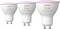 Drie Philips Hue witte en gekleurde slimme lampen met een GU10-fitting, met een roze licht bovenop, variërend in grootte van links naar rechts.