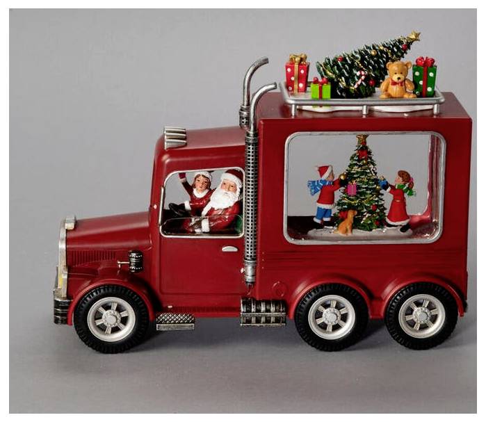 Een rode speelgoedtruck met de Kerstman achter het stuur, en een feestelijk kerstlandschap met een kerstboom en cadeaus afgebeeld in het raam van de aanhanger.