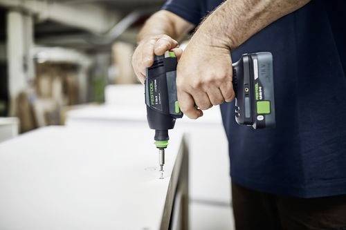Een persoon gebruikt een elektrische boormachine om een schroef in een stuk hout te draaien, met de nadruk op precisie en controle in een werkplaatsomgeving.