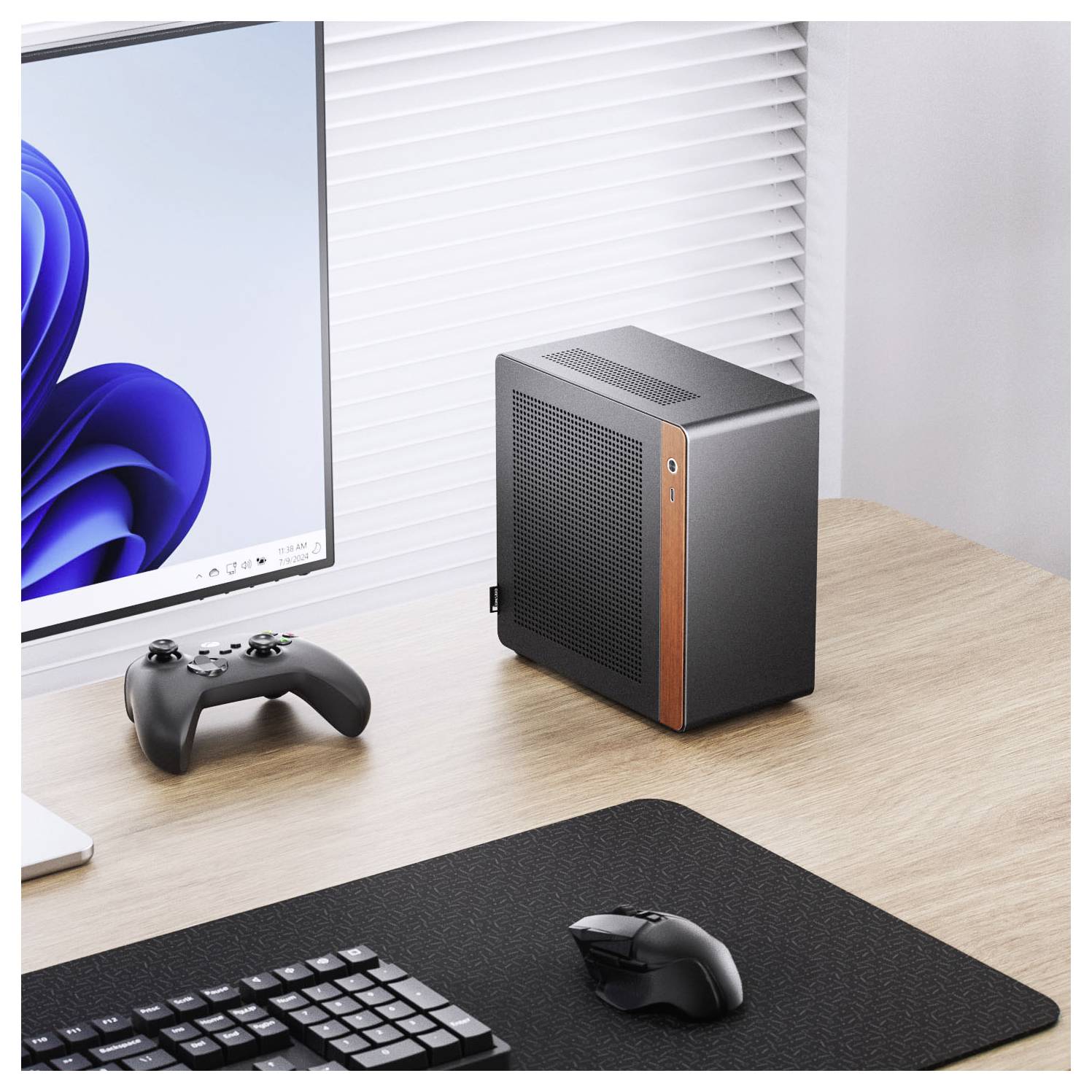 Een strak computersysteem met een monitor waarop een blauwe geometrische wervelontwerp wordt weergegeven, een draadloze gamecontroller, een toetsenbord en een compacte, moderne desktopcomputer.