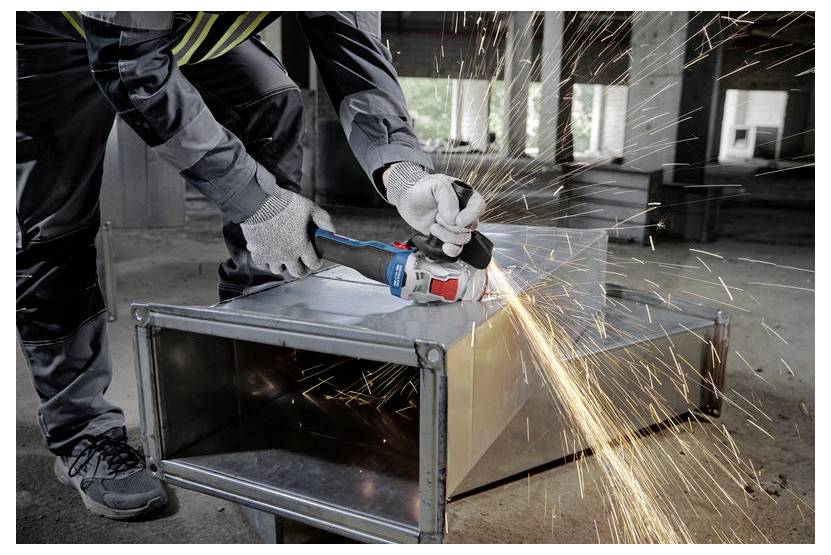 Een persoon die beschermende uitrusting draagt, gebruikt een haakse slijper en produceert vonken terwijl hij metaal aan het doorslijpen is in een industriële omgeving.
