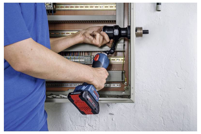 Een persoon in een blauwe shirt gebruikt een boormachine om een metalen paneel met draden van binnen te openen.