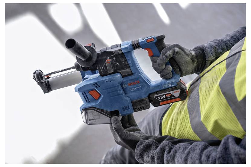 Persoon die een Bosch 18V draadloze roterende hamerboormachine gebruikt, met handschoenen en een veiligheidsvest, ter demonstratie van het gebruik van elektrisch gereedschap en veiligheid.