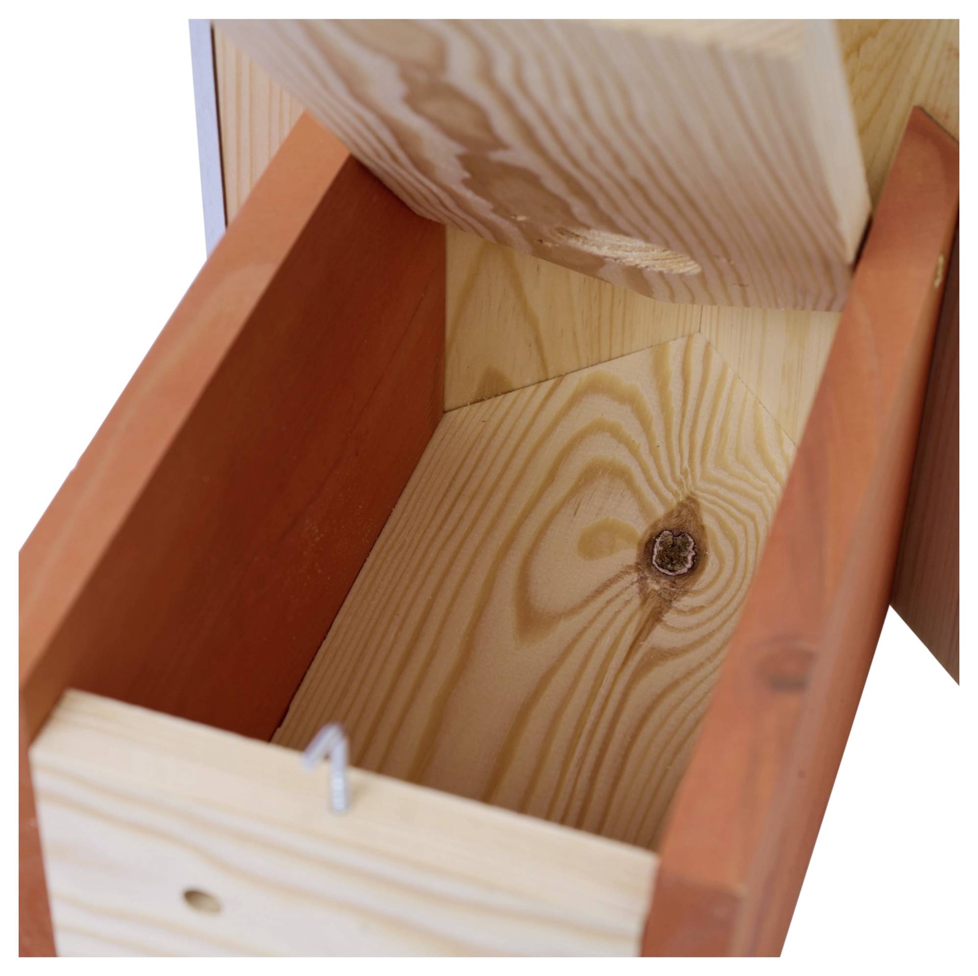 De afbeelding toont een open houten vogelhuisje met een schuin dak, waarvan de binnenkant leeg en eenvoudig is. Het hout heeft een knoop en lichte nerftextuur.