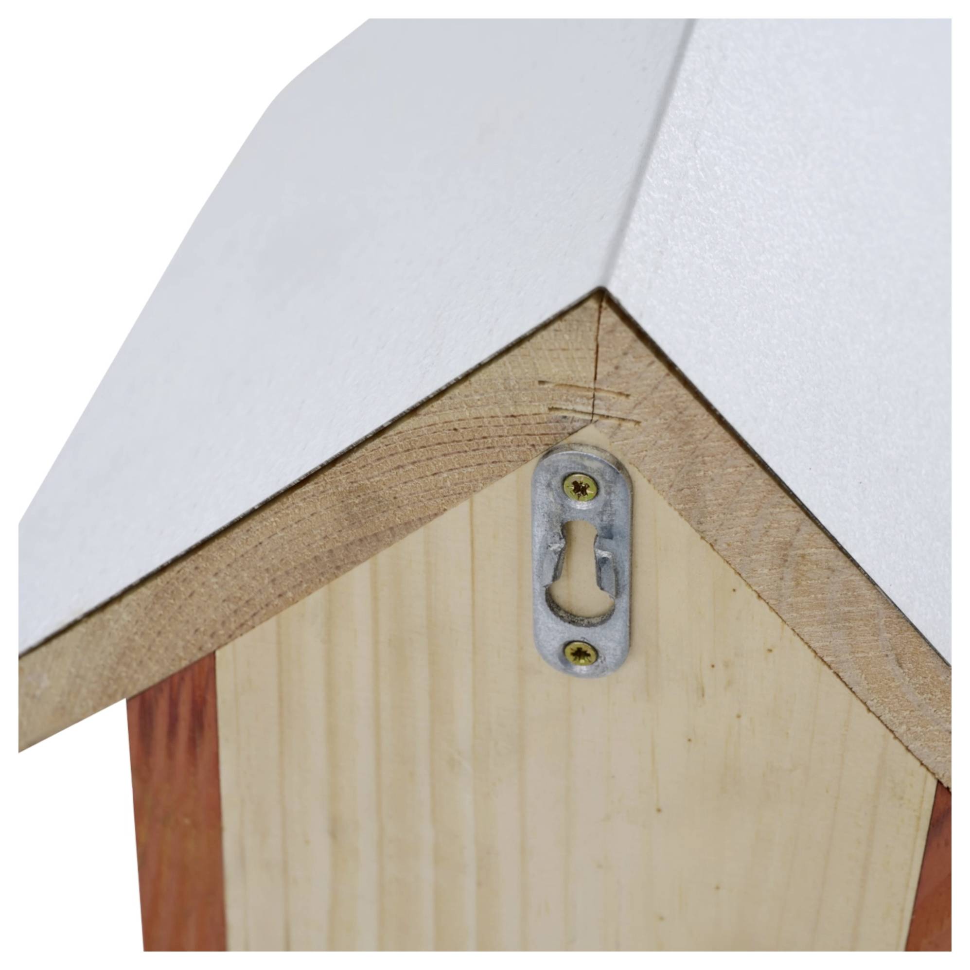 Close-up van een houten vogelhuisje dakhoek met een metalen beugel voor wandmontage. Het dak heeft een witte oppervlakte en een driehoekige vorm.