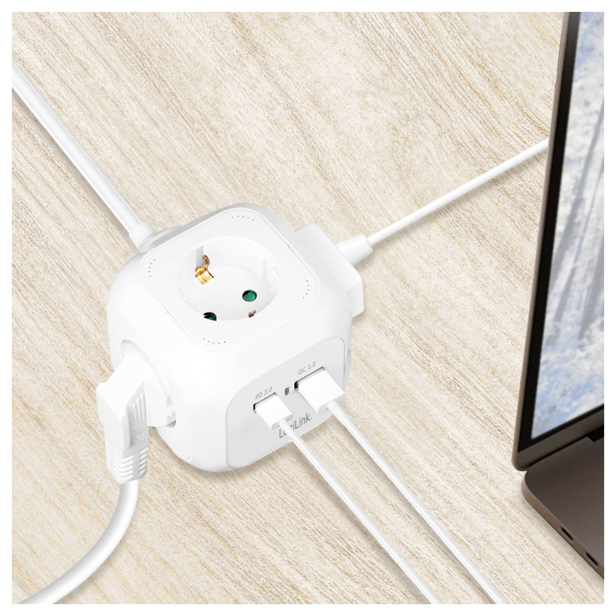 Een witte stekkerdoos met drie USB-poorten en meerdere stopcontacten staat op een houten oppervlak, gedeeltelijk zichtbare laptop rechts, kabels aangesloten.