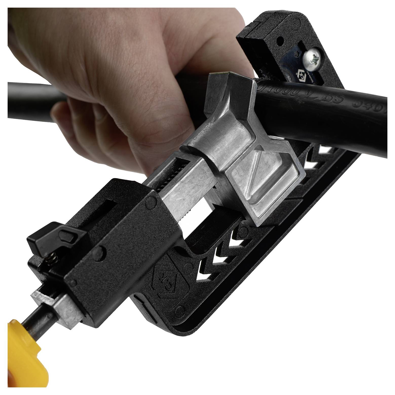 Een persoon gebruikt een gereedschap om de isolatie van een zwarte kabel te verwijderen, waarbij de metalen draad binnenin zichtbaar wordt. De hand oefent druk uit op het apparaat.