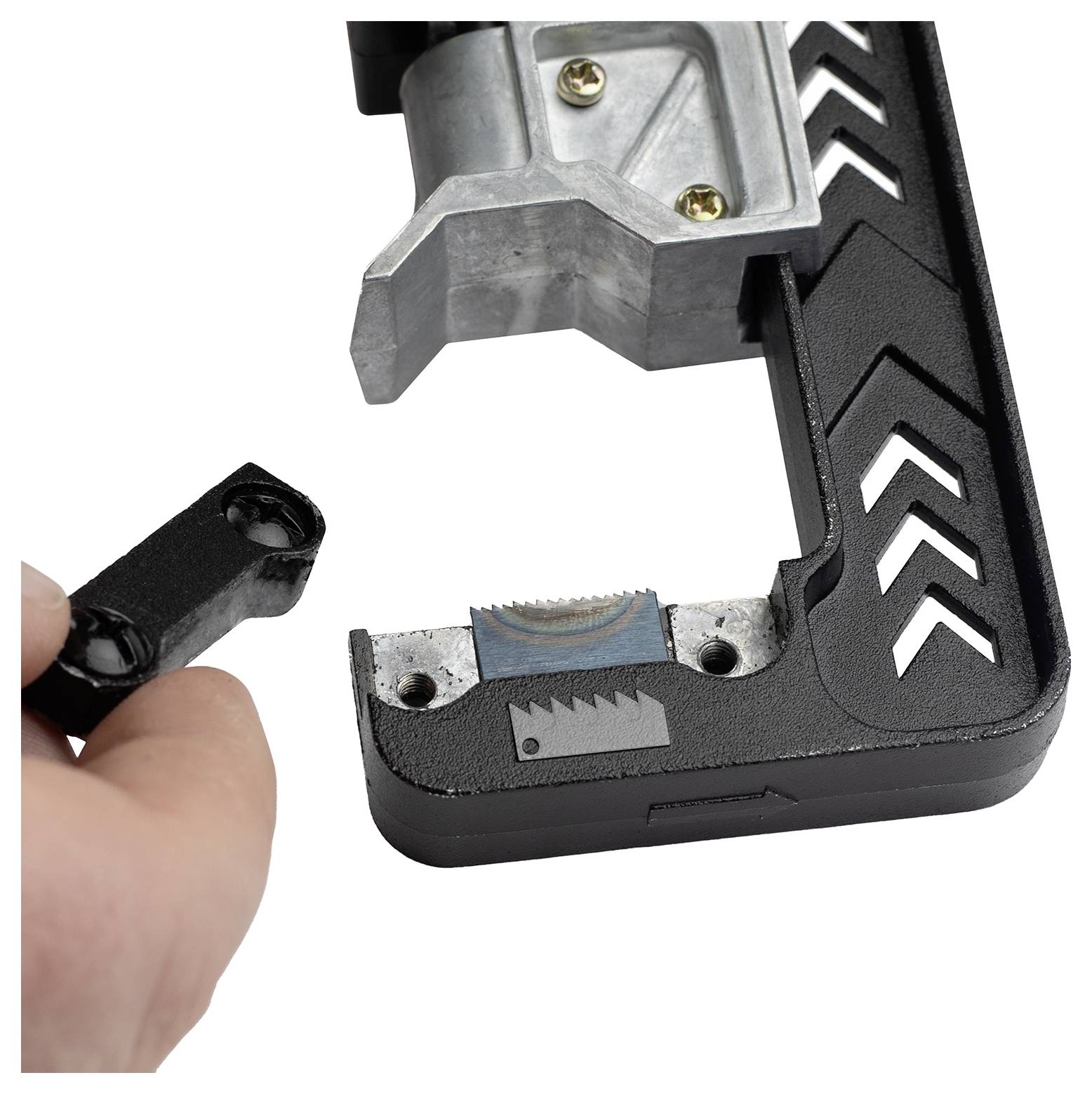 Een hand houdt een zwart onderdeel vast nabij een gedeeltelijk geassembleerd gereedschap met een metalen lemmet. Het gereedschap heeft pijlpatronen en zichtbare schroeven.