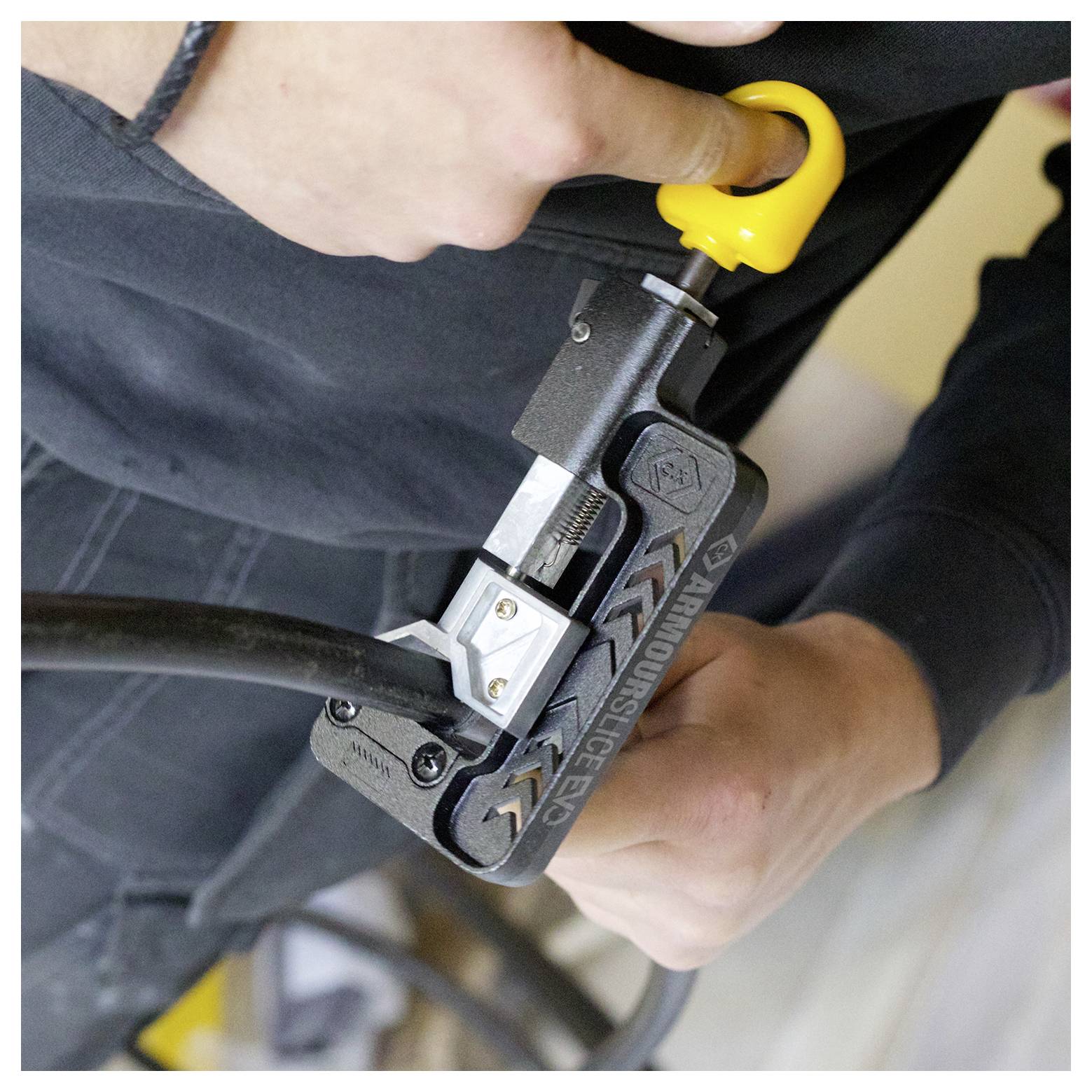 Een persoon gebruikt een draagbaar gereedschap om een kabel door te snijden, waarbij de nadruk wordt gelegd op het mechanisme van het gereedschap en de grip.