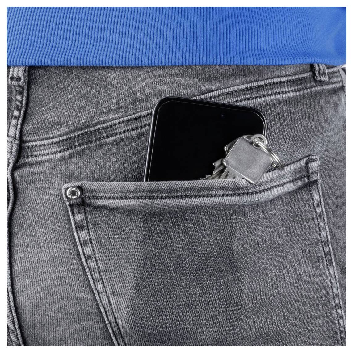 Een smartphone en een set sleutels zijn gedeeltelijk zichtbaar in de achterzak van een grijze spijkerbroek, met daarboven een blauw shirt.