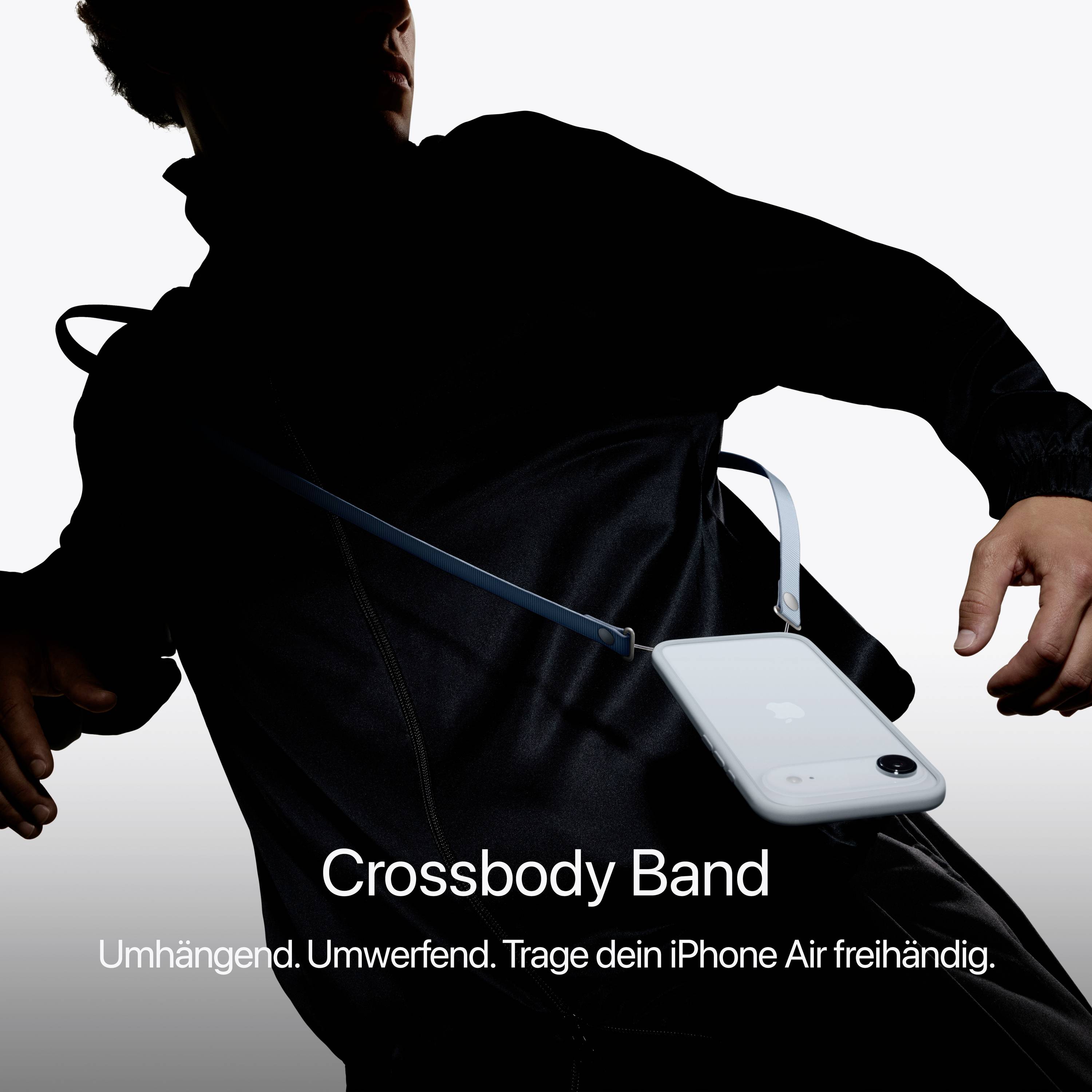 Een persoon draagt een zwart bovenkleding in de schaduw, toont daarbij de 'crossbody band' met een iPhone eraan bevestigd.