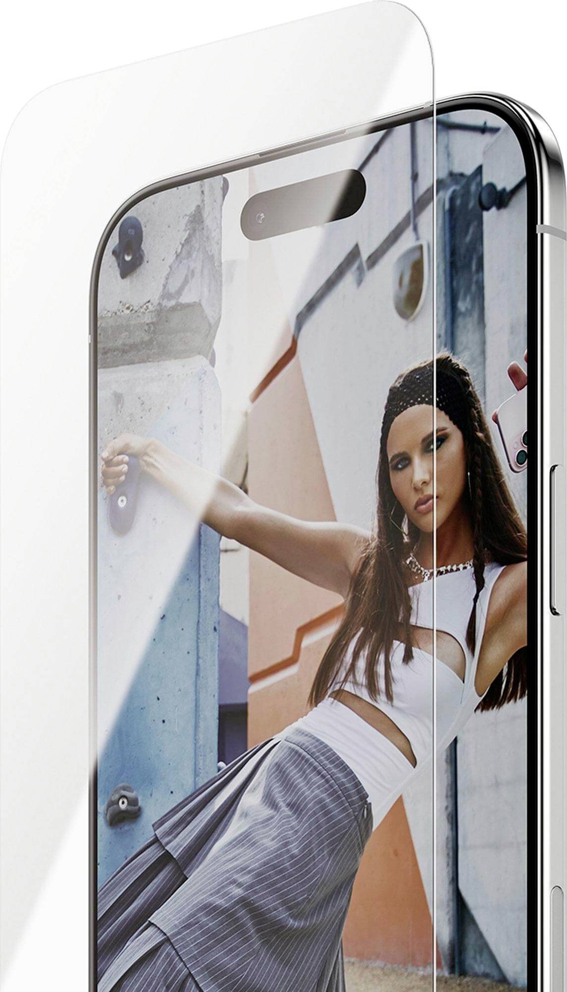 Een smartphone met een transparante schermbeschermer, waarop een afbeelding te zien is van een vrouw in een stijlvolle outfit die poseert tegen een kleurrijke stedelijke achtergrond.