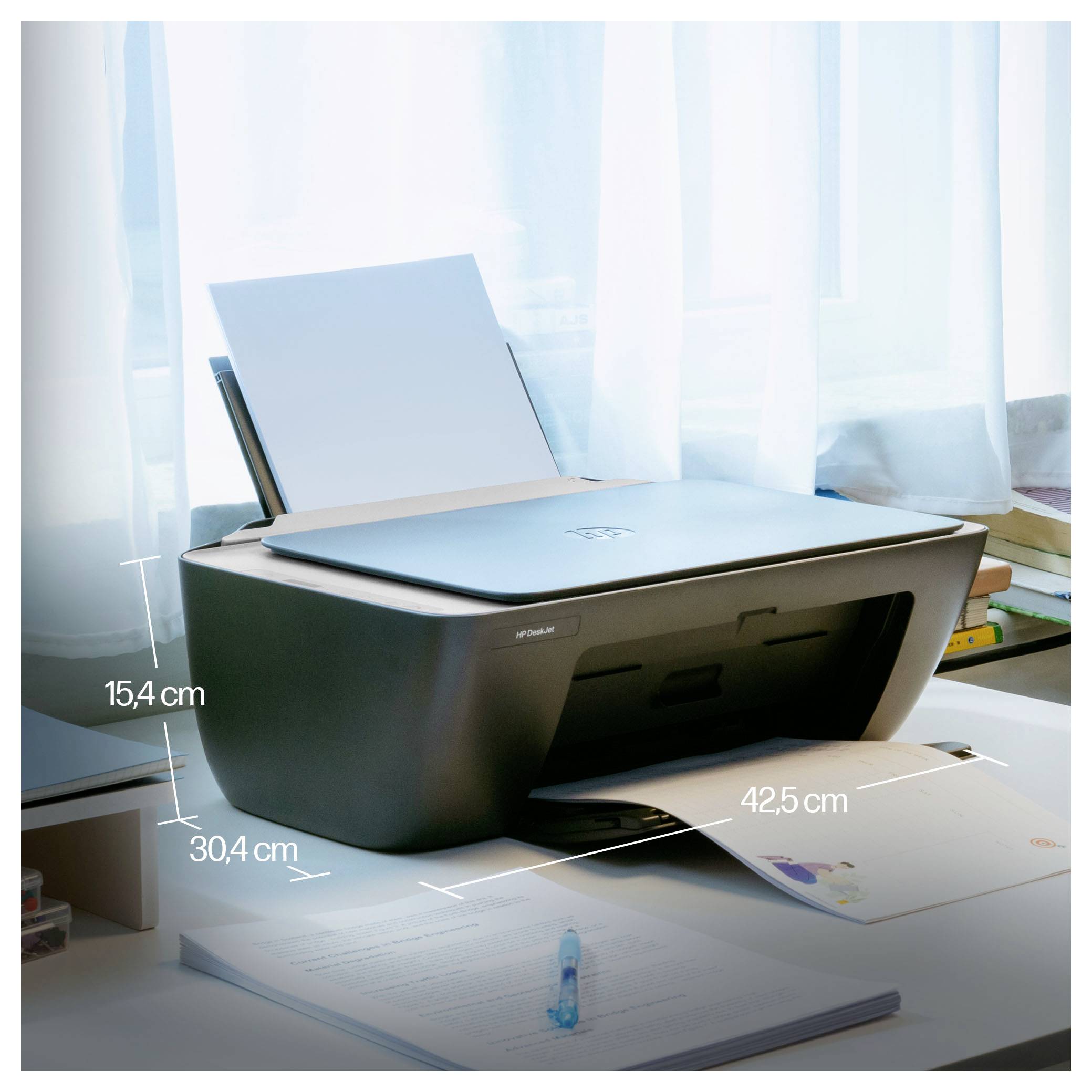 Kleine alles-in-één printer op een bureau met papier dat eruit voedert, met grootteetiketten '15,4 cm', '30,4 cm' en '42,5 cm'.