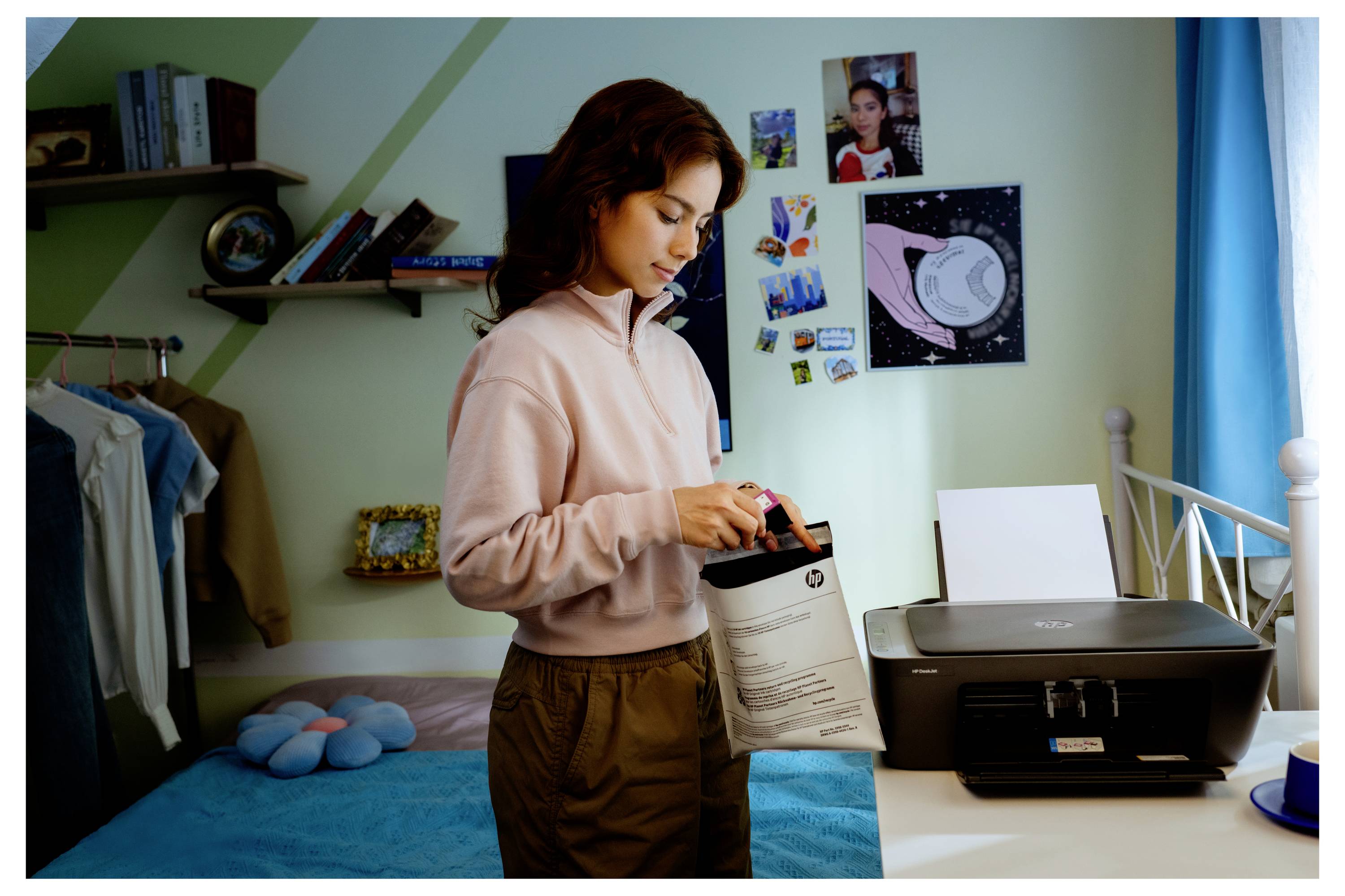 Jonge vrouw die in een slaapkamer staat en papier in een printer naast een bureau laadt, wat suggereert dat zij zich voorbereidt op het afdrukken van documenten.