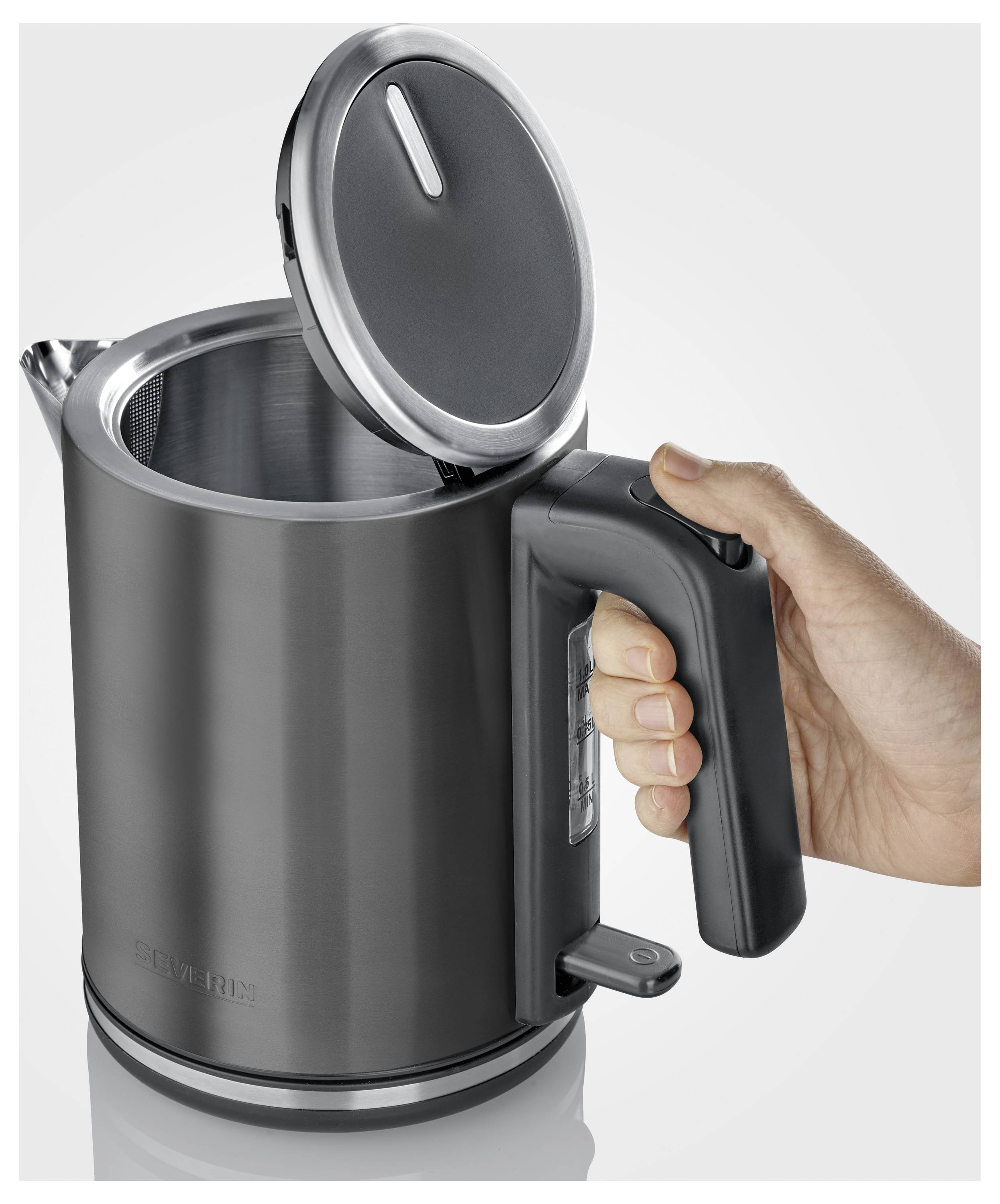 Een persoon houdt een grijze elektrische waterkoker vast met een open deksel, waarbij het interieur zichtbaar is. De waterkoker heeft een handgreep en een knop nabij de onderkant.