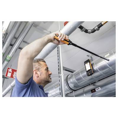 Een man gebruikt een draagbaar apparaat om de HVAC-luchtkanalen te inspecteren in een industriële omgeving, waarbij hij zorgt voor een goede ventilatie en onderhoud.