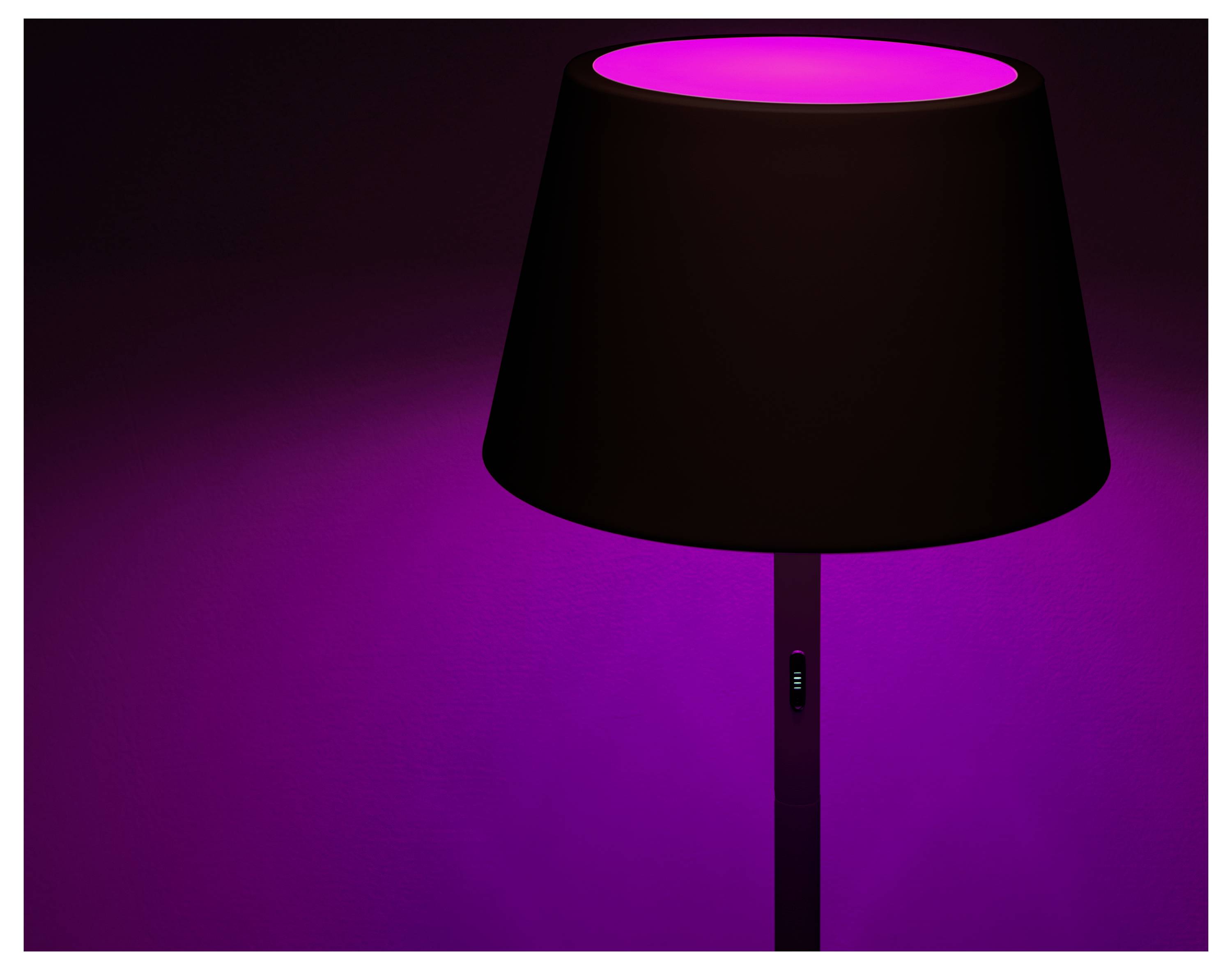 Een vloerlamp verspreidt een levendig roze licht, waardoor een warme sfeer ontstaat tegen een donkere achtergrond.