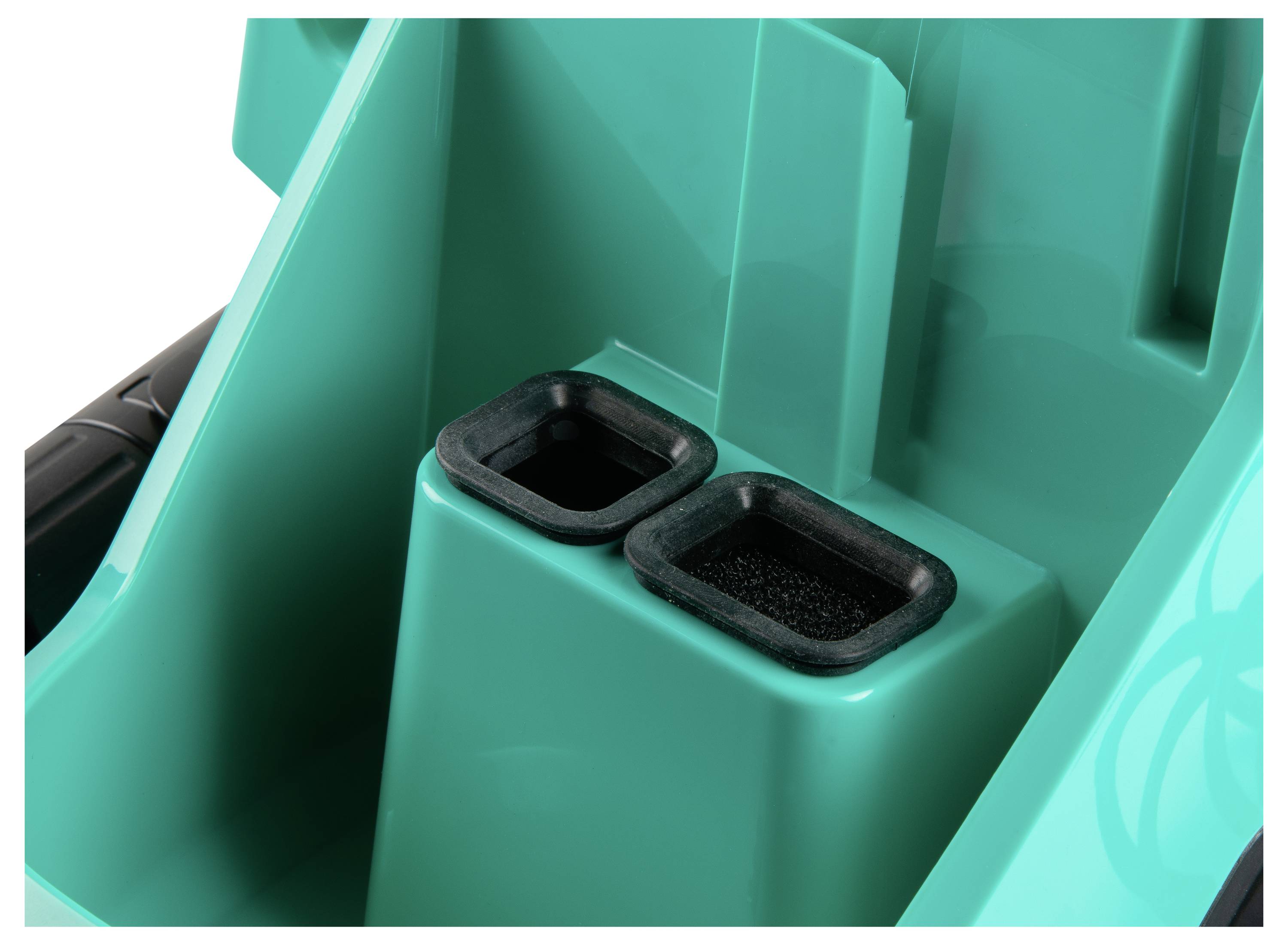 Close-up van twee rechthoekige zwarte rubberen inzetstukken op een groen plastic oppervlak, mogelijk onderdelen van een gereedschap of apparaat.