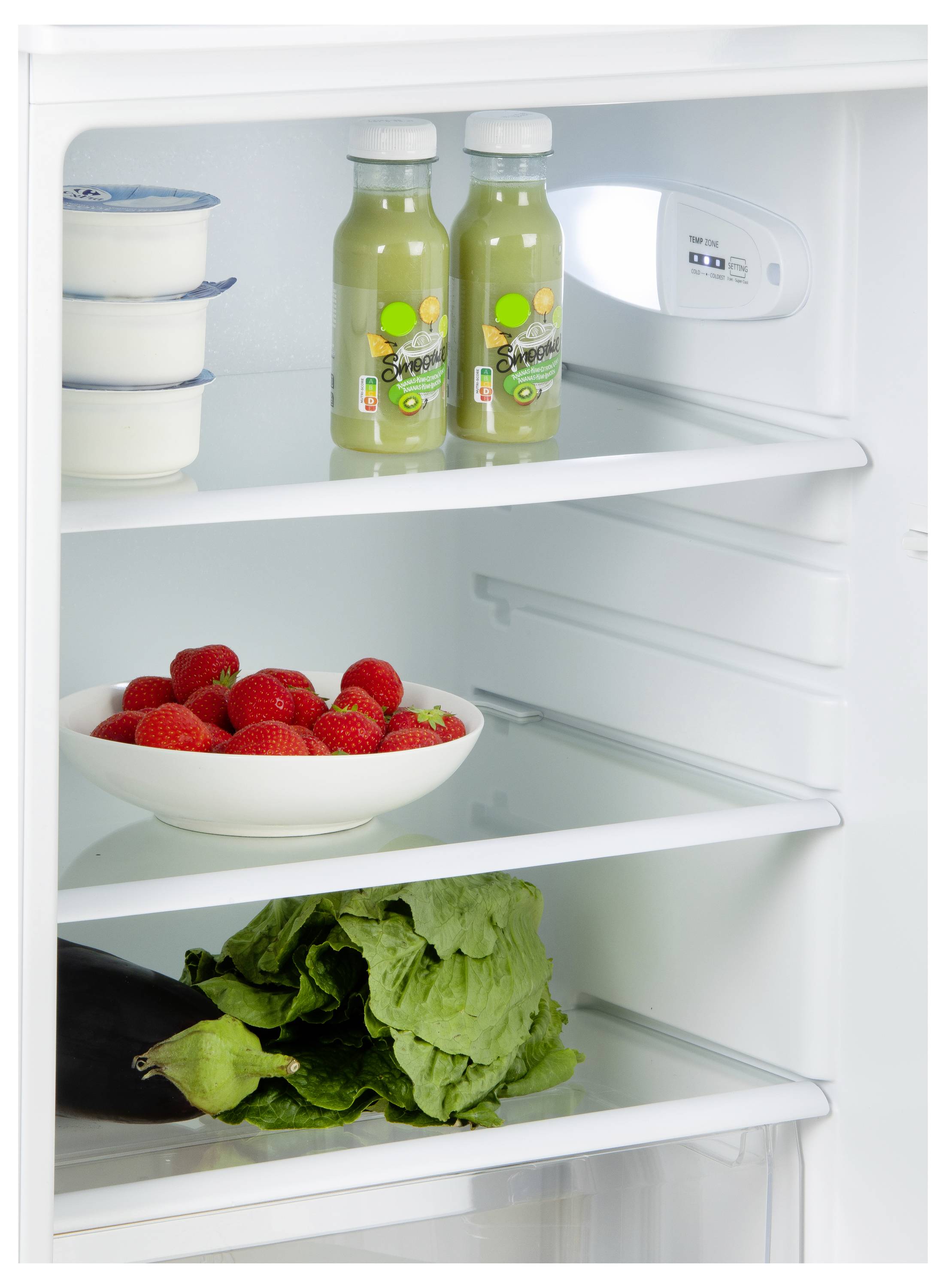 Een openstaande koelkast met twee flessen sap, yoghurtcontainers, een kom met aardbeien, sla en een aubergine op verschillende schappen.