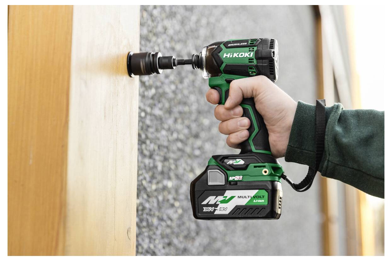 Een persoon die een groene en zwarte snoerloze boormachine gebruikt om een gat te maken in een houten oppervlak. Op de boormachine staat 'HiKOKI Multi Volt.'