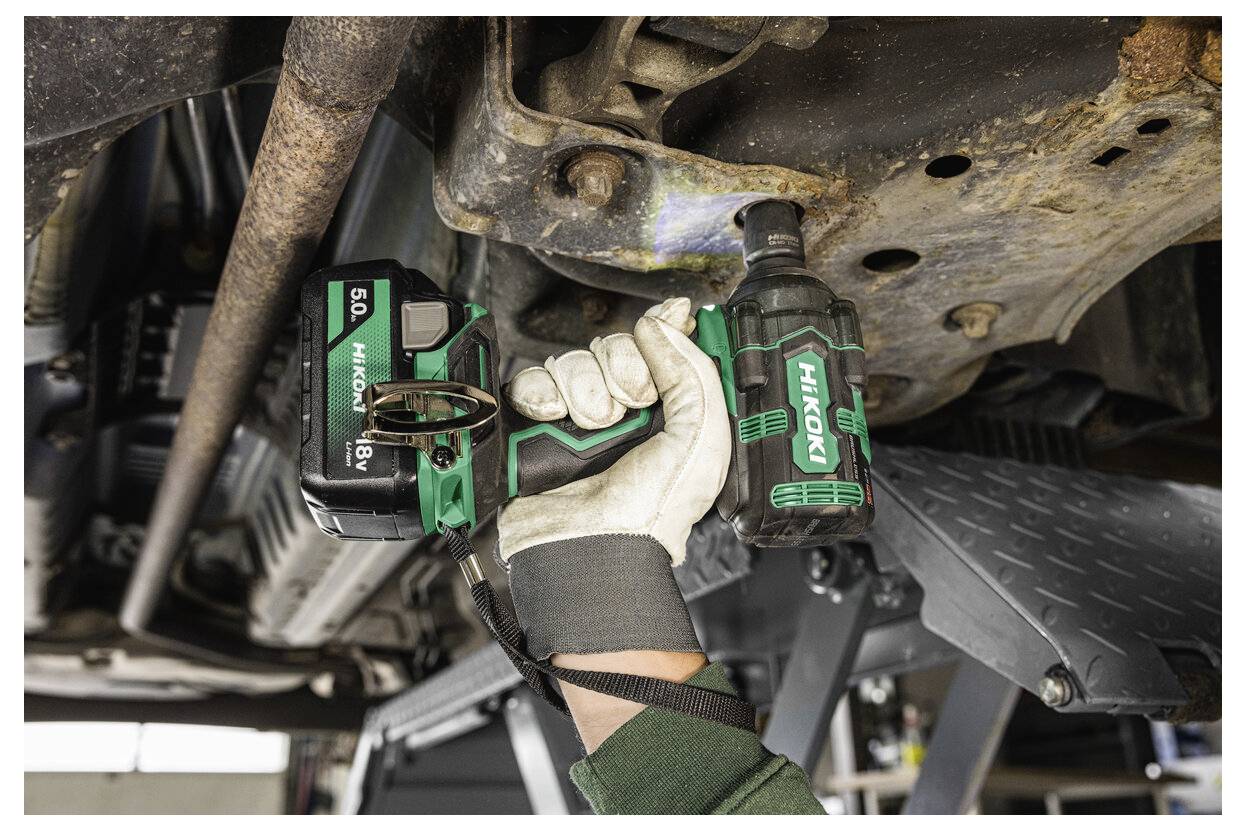 Persoon die een snoerloze slagmoersleutel gebruikt om aan de onderkant van een voertuig te werken, waarbij automotive reparatie of onderhoudswerk wordt benadrukt.