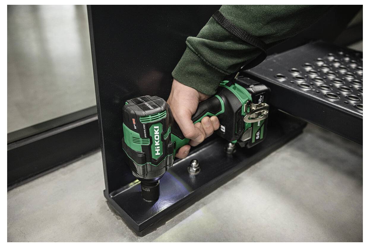 Een persoon gebruikt een groene draadloze slagschroevendraaier met het label 'HiKoki' om een schroef vast te zetten op een metalen constructie, waarbij het nut ervan in de bouw wordt getoond.