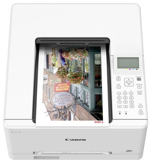 Een witte Canon-printer met een kleurenfoto van een winkelverzicht gedeeltelijk afgedrukt, waarop bloemendecoraties en een 'Regal' bord zichtbaar zijn.