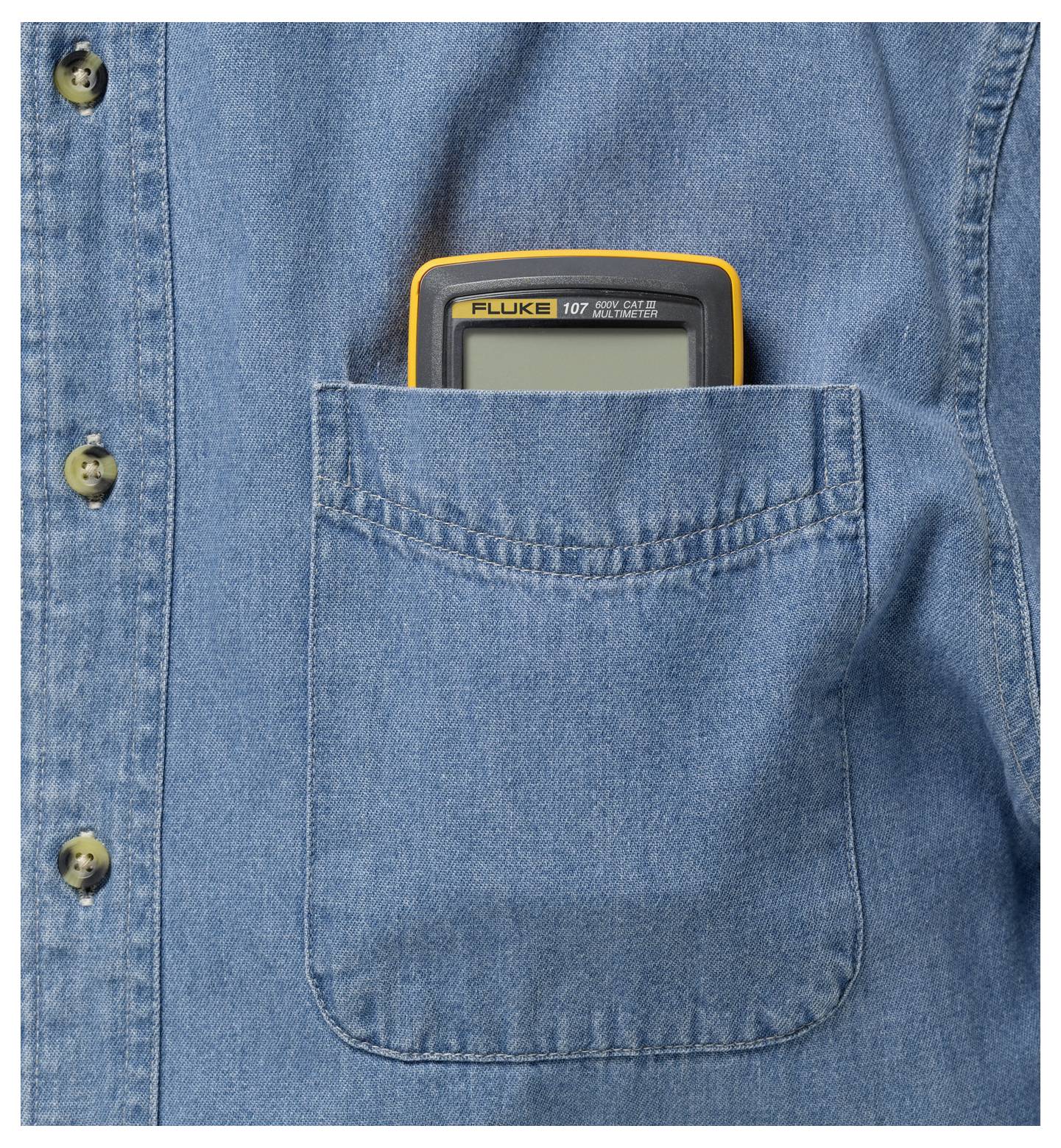 Een multimeter met een gele rand zit opgeborgen in de borstzak van een blauw spijkerhemd.