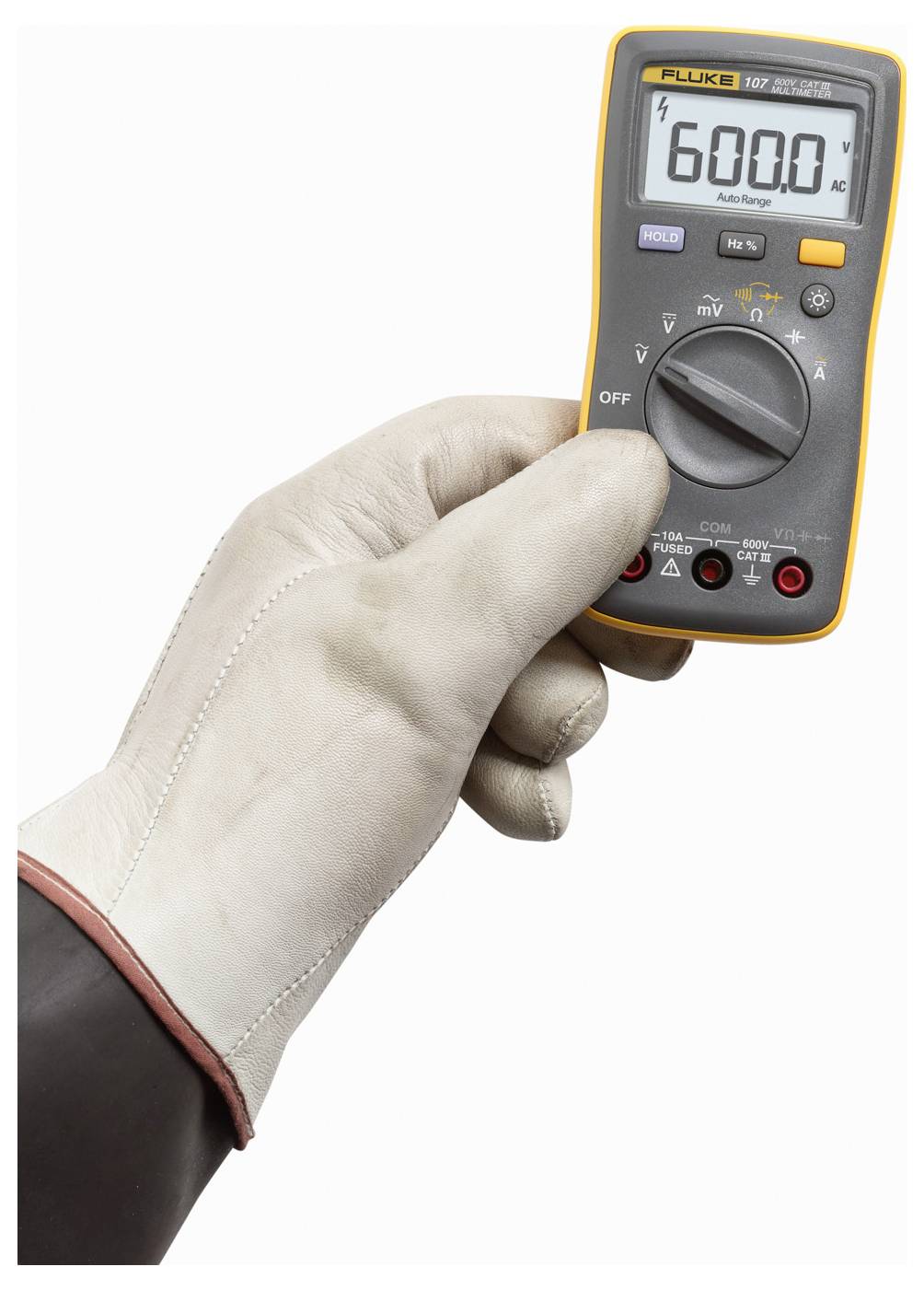 Een hand met een witte handschoen houdt een digitale multimeter vast die '600.0' toont, wat een wisselstroomspanningsmeting aangeeft.